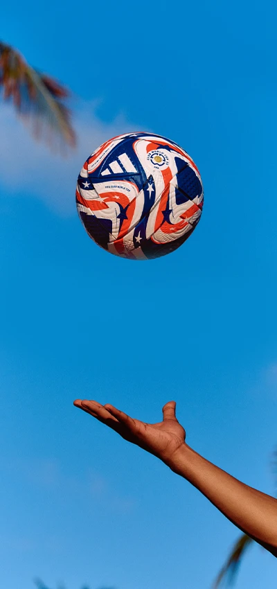 This image shows a person with their arm extended holding a soccer ball. The sky is in the background, suggesting it might be outdoors during the daytime.