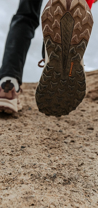 The image shows a foot with a hiking boot stepped into a pile of soil or gravel, suggesting the person is outdoors, possibly on some sort of trail or mountainous terrain.