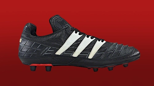 The image shows a pair of black football cleats on display.