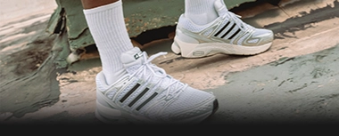 Person trägt weiße adidas Sneaker im Urban-Setting. (Foto)