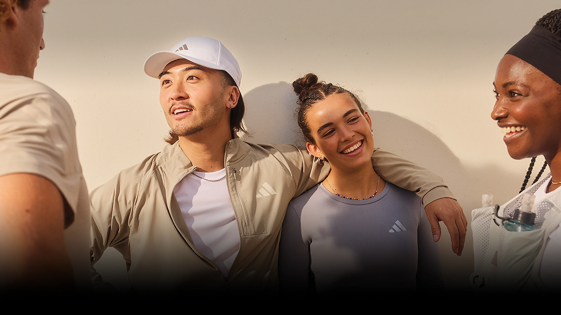 Gruppe junger Erwachsener in adidas Sportbekleidung im Gespräch. (Foto)