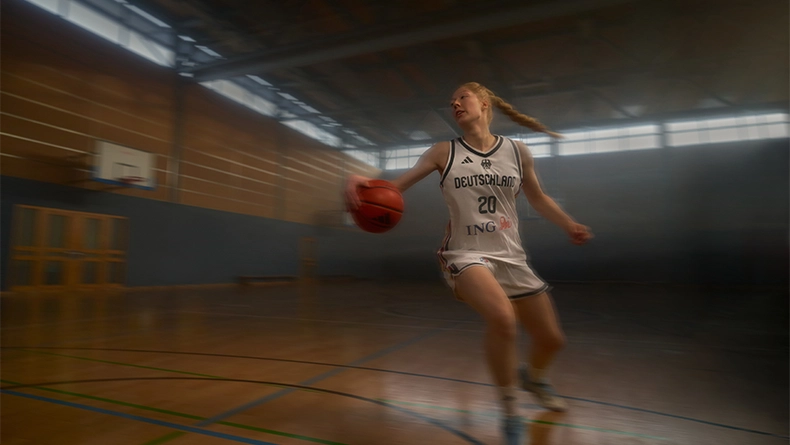 Frau im weißen Deutschland-Basketballtrikot beim Dribbling in einer Sporthalle. (Foto)