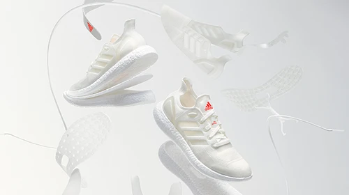 Zwei weiße adidas Laufschuhe in schwebender Darstellung. (Foto)