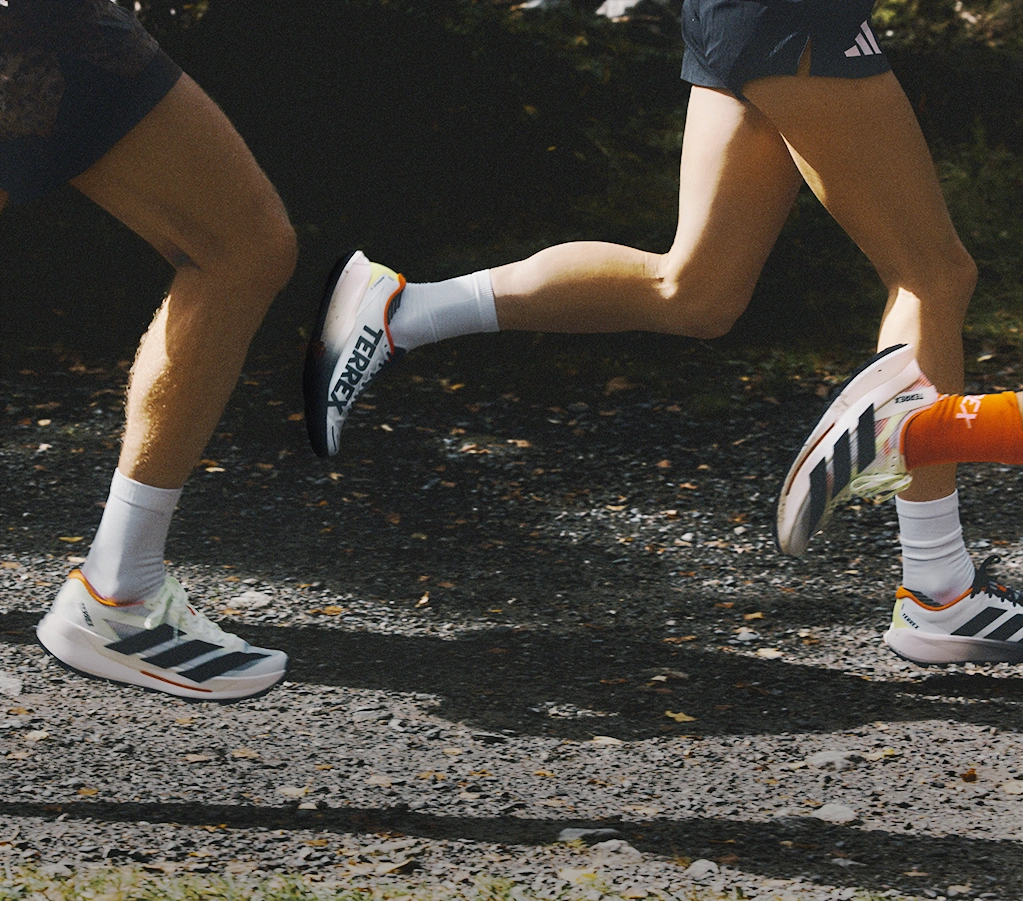 Two people running on a forest path wearing adidas shoes. (Photo)
