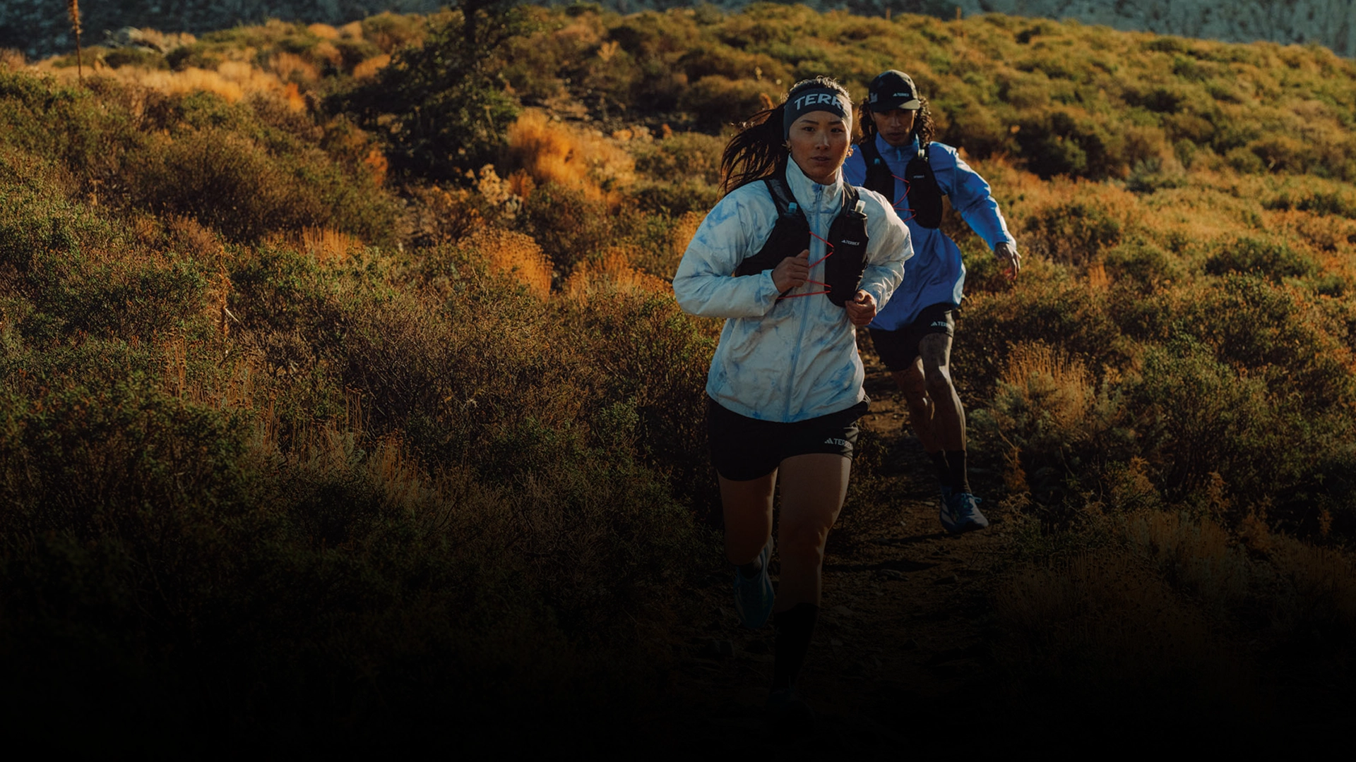 Two runners trail running in a mountainous landscape. (Photo)