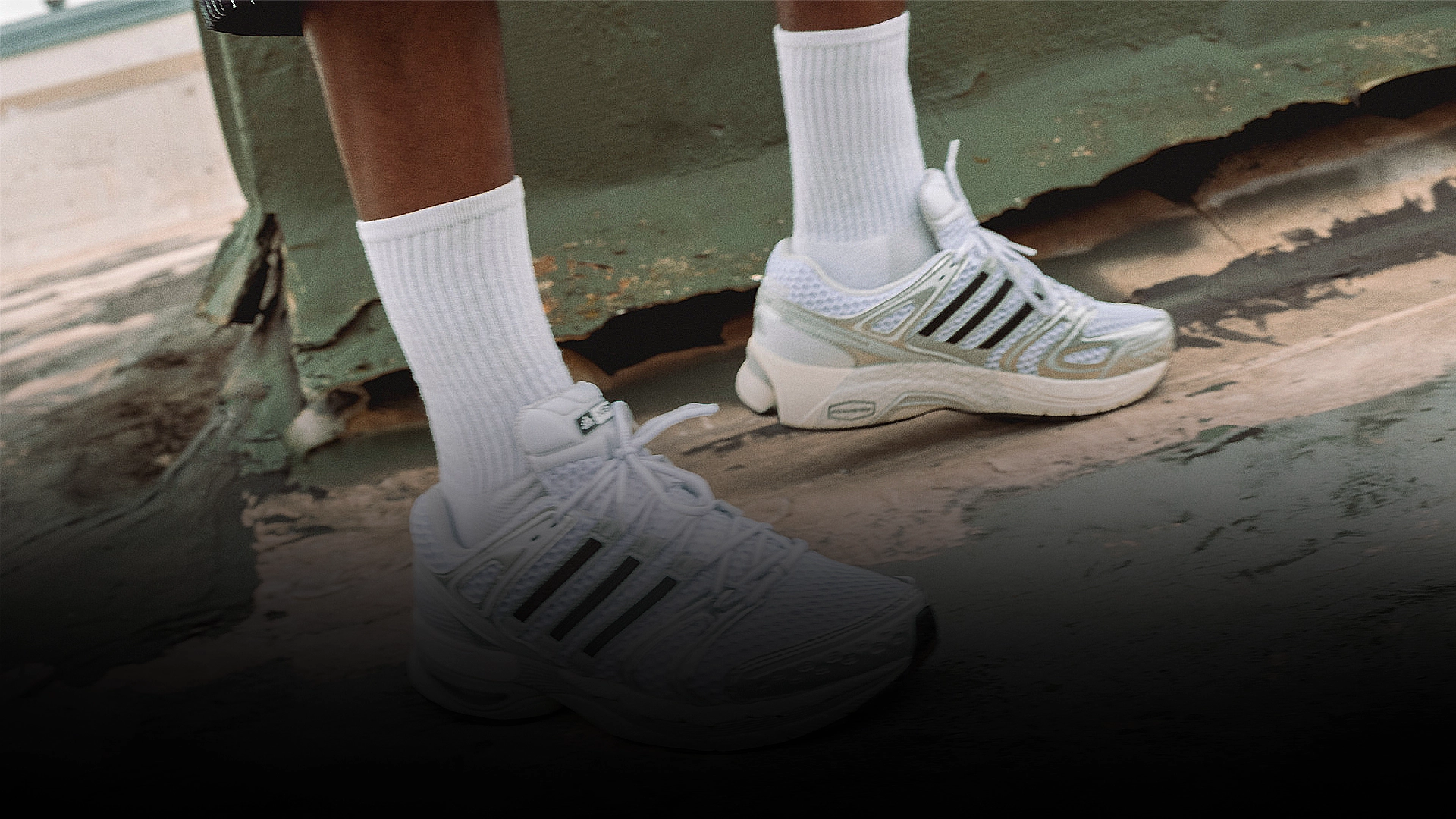 Person wearing white adidas sneakers in an urban setting. (Photo)